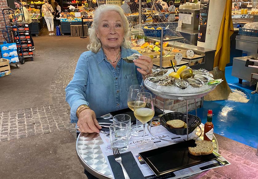 Helga dégustant des huîtres et un vin blanc frais sur la place du Vieux-Marché
