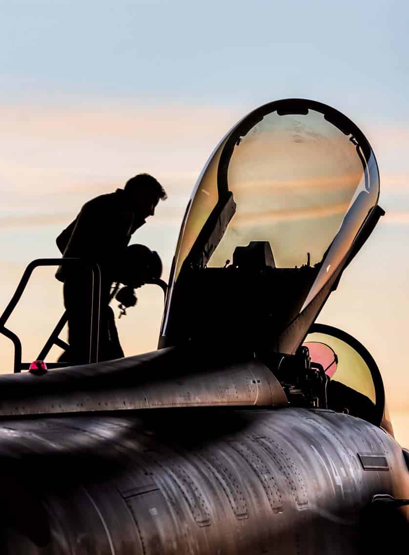 Pilote militaire montant à bord de son avion de chasse au coucher du soleil