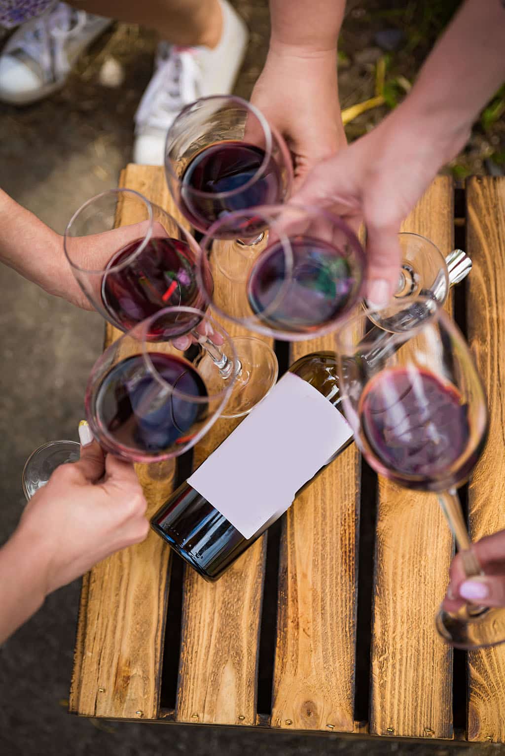 Les gens trinquent avec du vin sur la terrasse d'été d'un café ou d'un restaurant, une bouteille en verre dans les mains de différents horizons