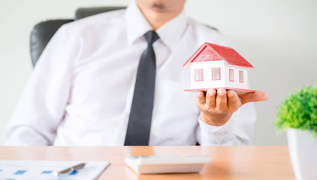 une personne tenant la maquette d'une maison dans sa main